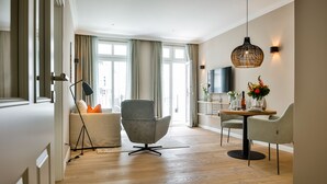 A modern living room with a sofa, armchair, dining table, and pendant light. - Neubau. Strandnah. Anspruchsvoll. Objekt-id: Ljw/05 (Westerland)