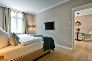 Ein modernes Schlafzimmer mit Bett, Fernseher und einem Essbereich mit Tisch und Stühlen.