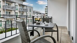 A balcony with a table, chairs, and a vase of flowers. - Neubau. Strandnah. Anspruchsvoll. Objekt-id: Ljw/07 (Westerland)