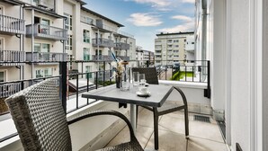 Un balcón con mesa y sillas, con vista a una zona residencial con varios edificios de apartamentos.