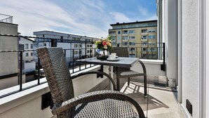 A balcony with wicker furniture, a table, and a vase of flowers.