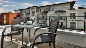 A balcony with wicker chairs and a table, overlooking a row of townhouses. - Neubau. Strandnah. Anspruchsvoll. Objekt-id: Ljw/11 (Westerland)