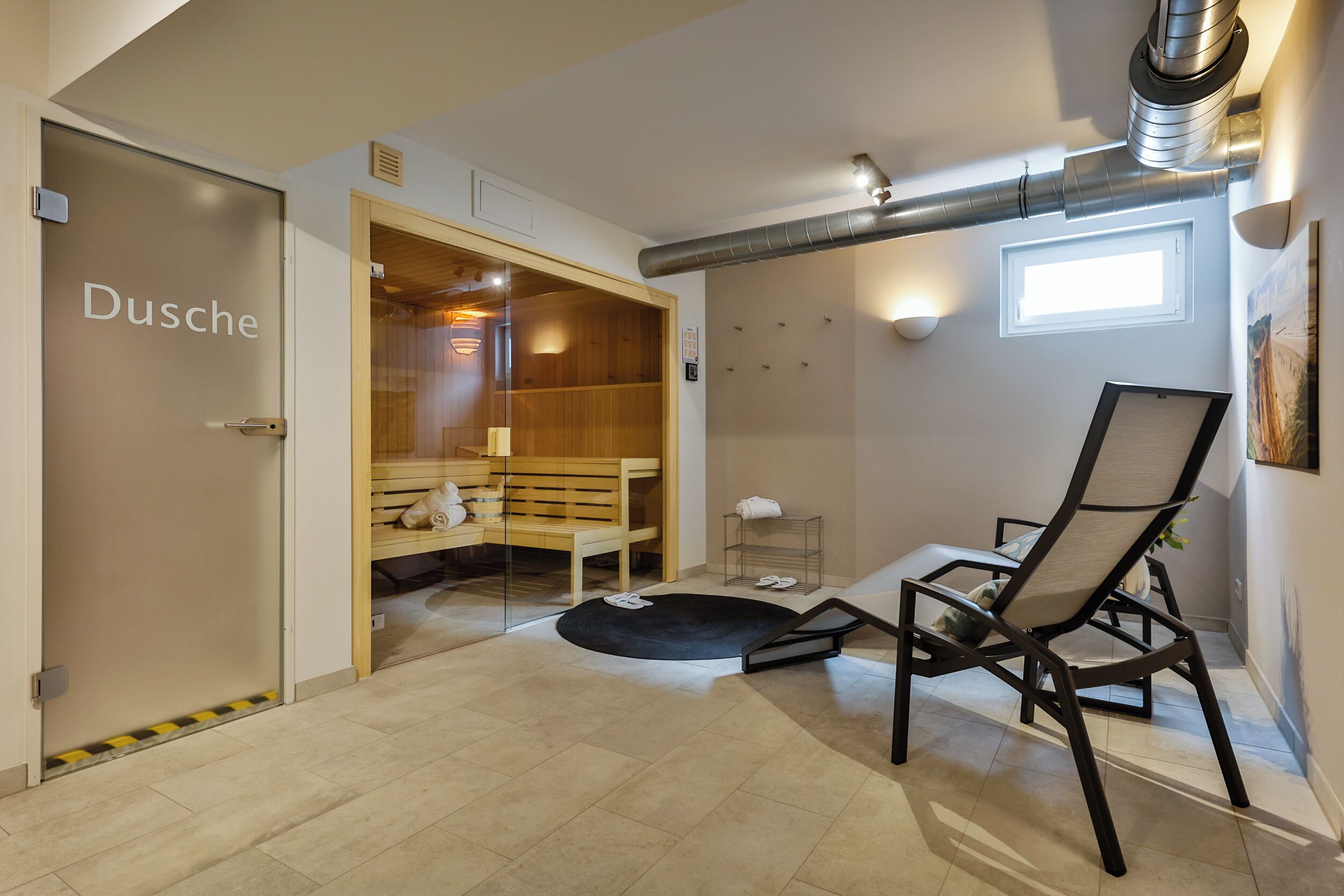 Une salle de spa équipée d’un banc en bois, d’une table de massage et d’une petite étagère où sont rangées les serviettes.
