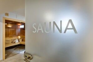 Eine Wand mit der Aufschrift "SAUNA" in großen Buchstaben, die einen Sauna-Bereich kennzeichnet.