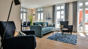 Un salon moderne comprenant un canapé, des fauteuils, une table basse et un lampadaire.