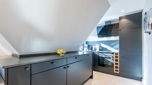 A modern kitchen with dark cabinetry, a built-in oven, and a stainless steel range hood.