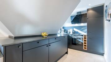A modern kitchen with dark cabinetry, a built-in oven, and a stainless steel range hood.