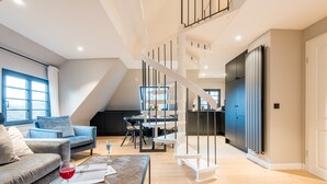 Una sala de estar moderna con una mesa de centro de madera, un sofá y un comedor con una escalera blanca.