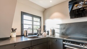 Una cocina moderna con horno empotrado, un ventanal grande y un comedor con una mesa dispuesta para dos personas.