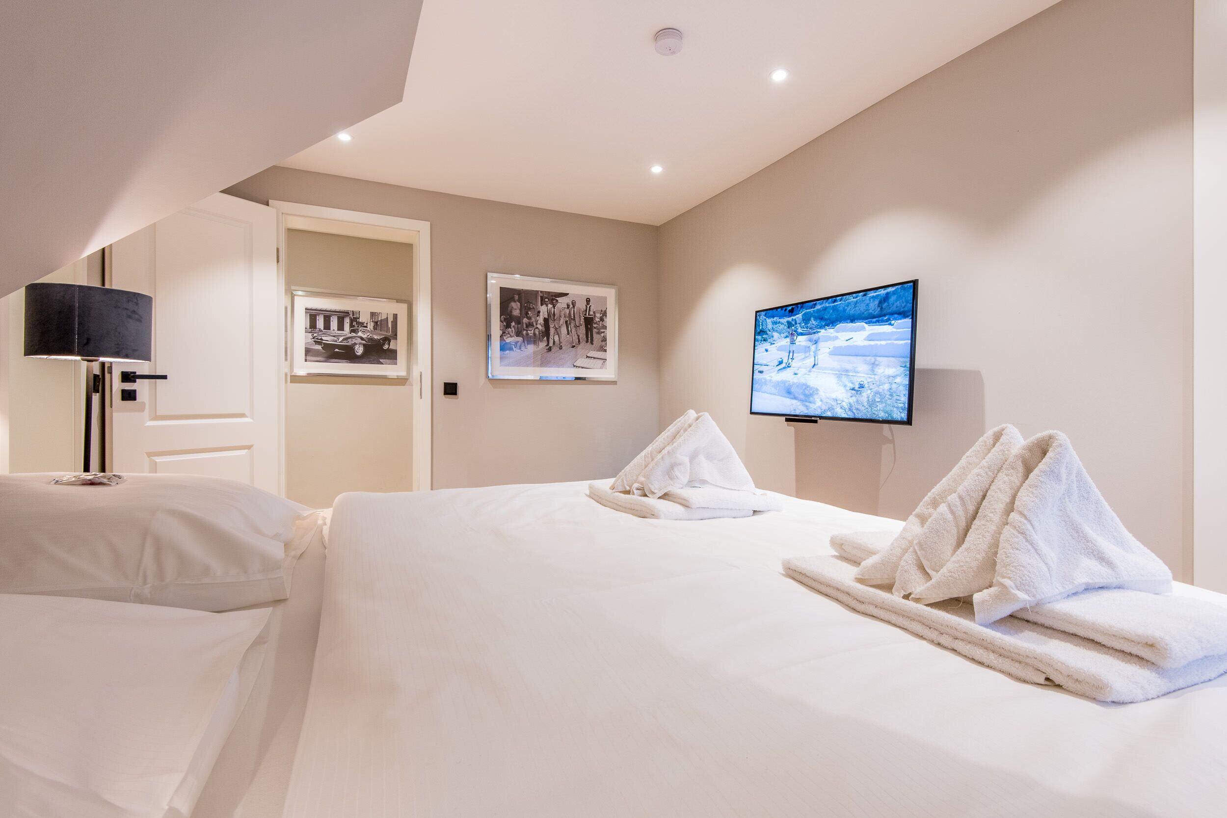 Une chambre d’hôtel avec un lit, une télévision et deux tableaux encadrés au mur.