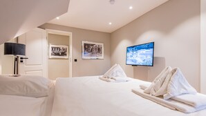 Una habitación de hotel con una cama, un televisor y dos cuadros en la pared.