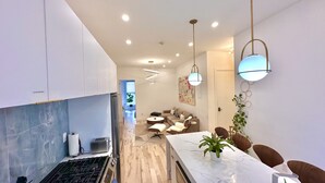 A modern kitchen with a marble countertop, a gas stove, and a dining area with a white table and chairs. - Lovely stylish suite in a historical Brooklyn area (Brooklyn)