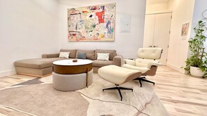 Ein modernes Wohnzimmer mit einem Ecksofa, einem runden Couchtisch und einem Relaxsessel.