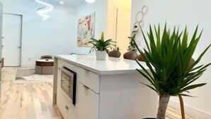 A modern kitchen with a central island, pendant lighting, and potted plants. - Lovely stylish suite in a historical Brooklyn area (Brooklyn)