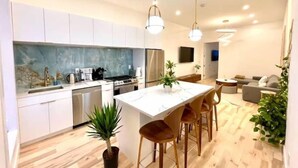 A modern kitchen with white cabinets, a central island, and pendant lighting. - Lovely stylish suite in a historical Brooklyn area (Brooklyn)