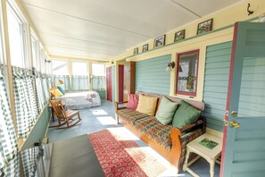 A cozy room with a wooden rocking chair, a colorful sofa, and a small table.