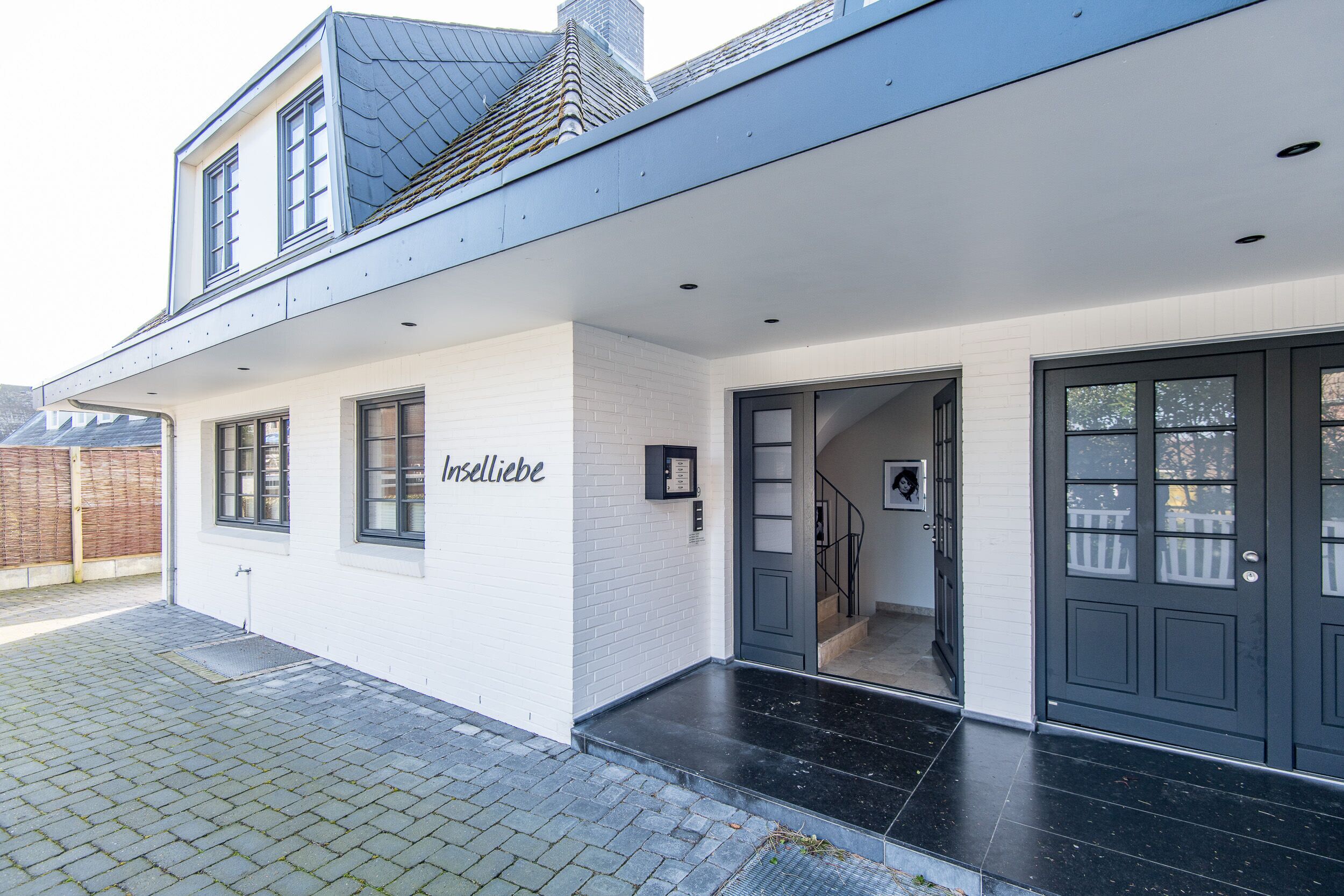 Ein modernes, zweistöckiges Haus mit weißer Fassade und dunklem Dach.