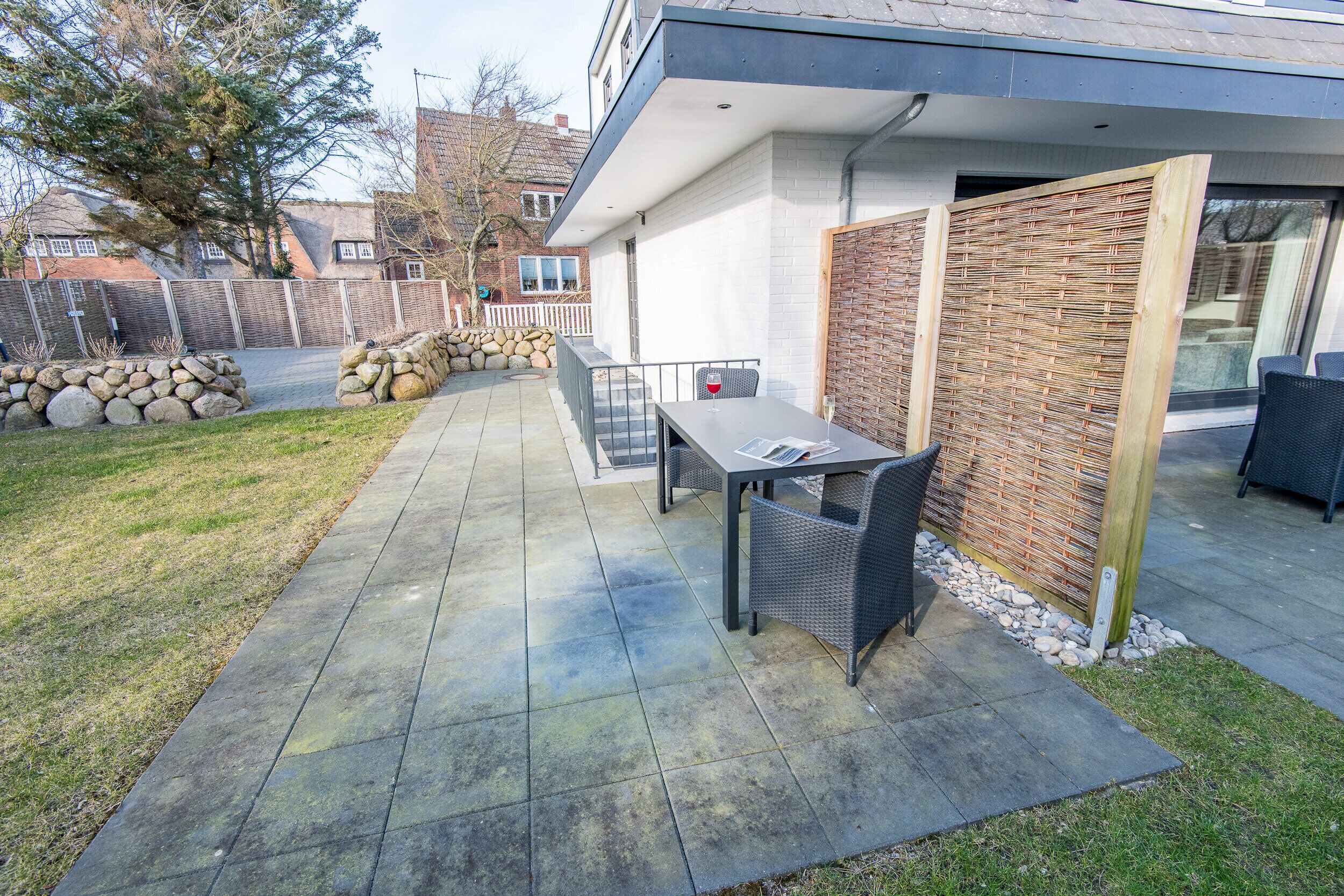 A patio with a table and chairs, a stone wall, and a wooden fence.