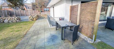 A patio with a table and chairs, a stone wall, and a wooden fence.