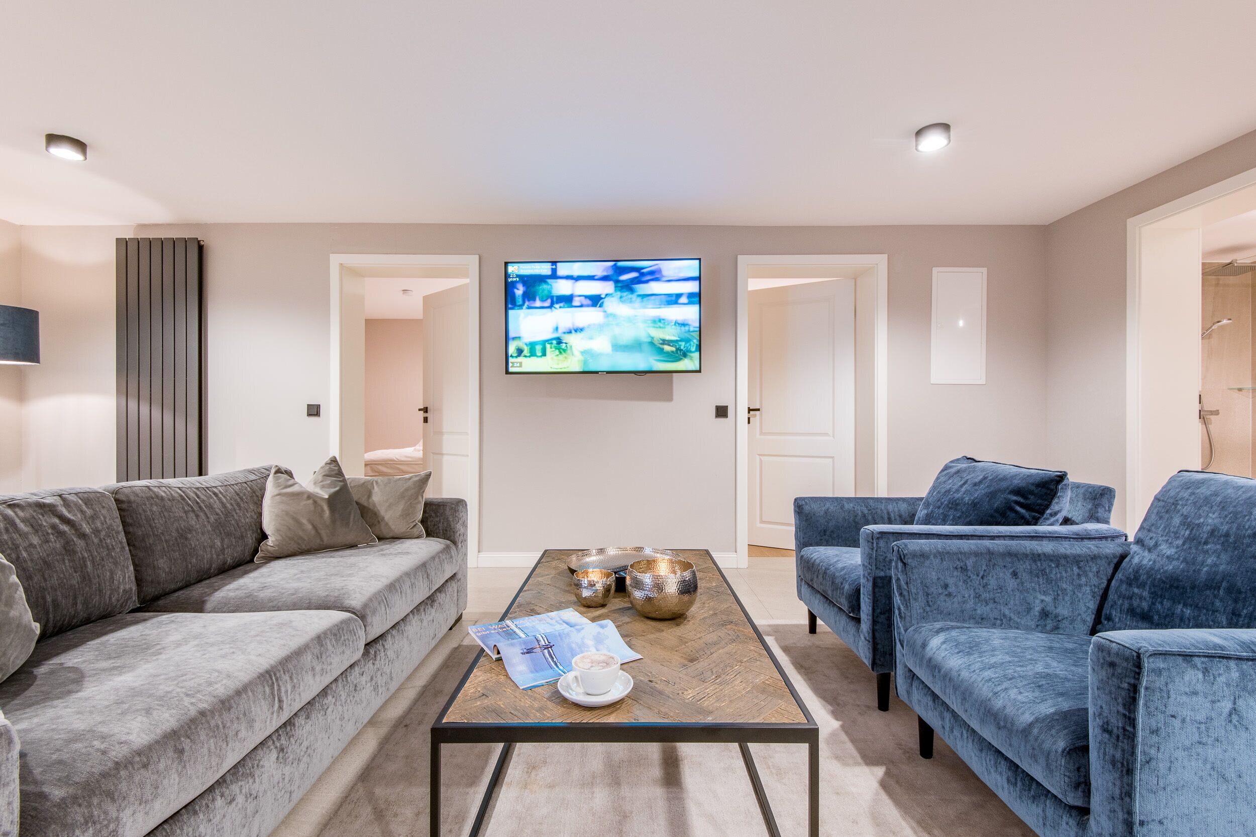 A modern living room with a grey sofa, a blue armchair, and a coffee table with decorative bowls.