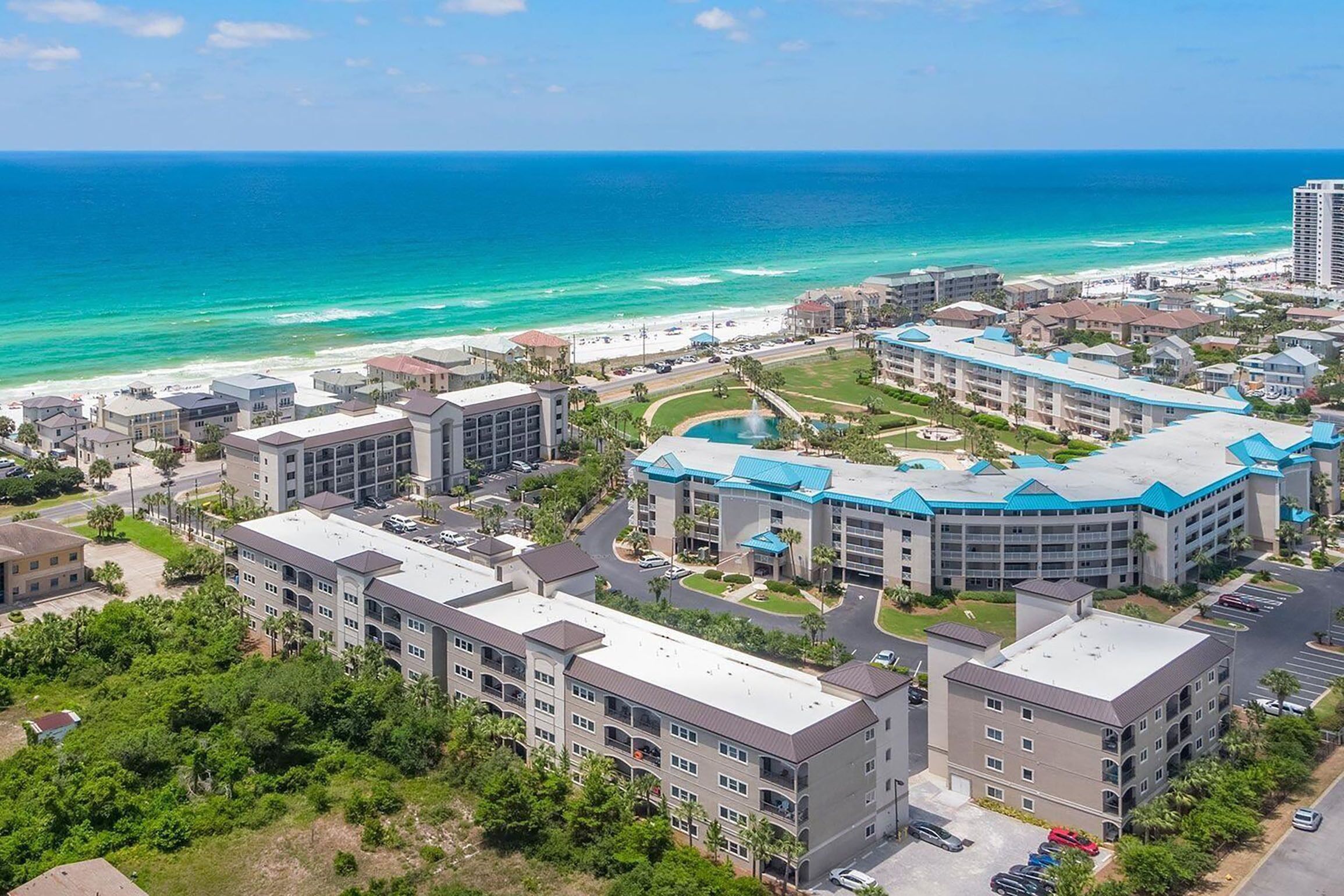 Complejo hotelero frente al mar, con varias construcciones, zona de estacionamiento y vistas a la playa y al océano.