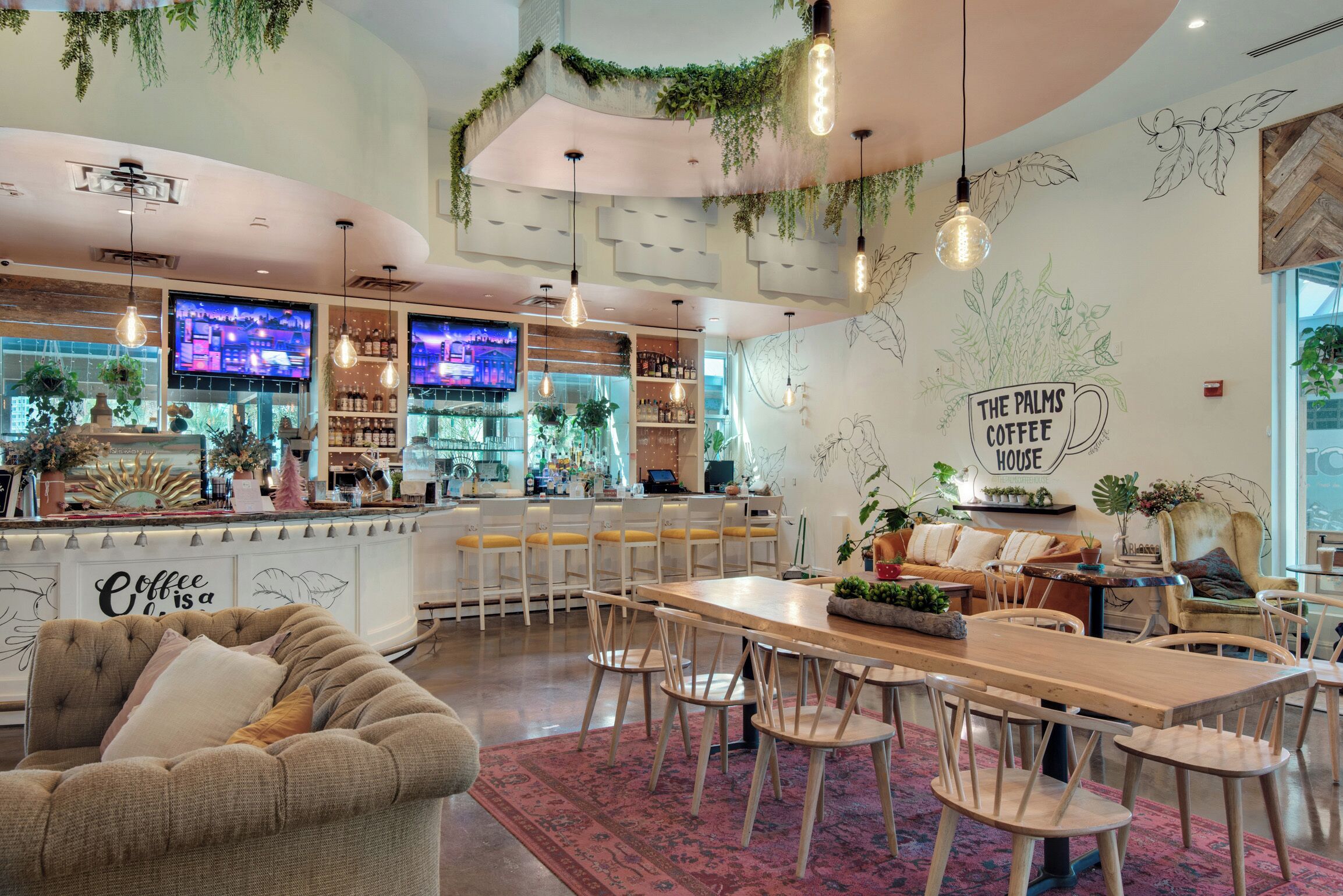 A modern coffee shop interior with a bar area, seating, and decorative plants.