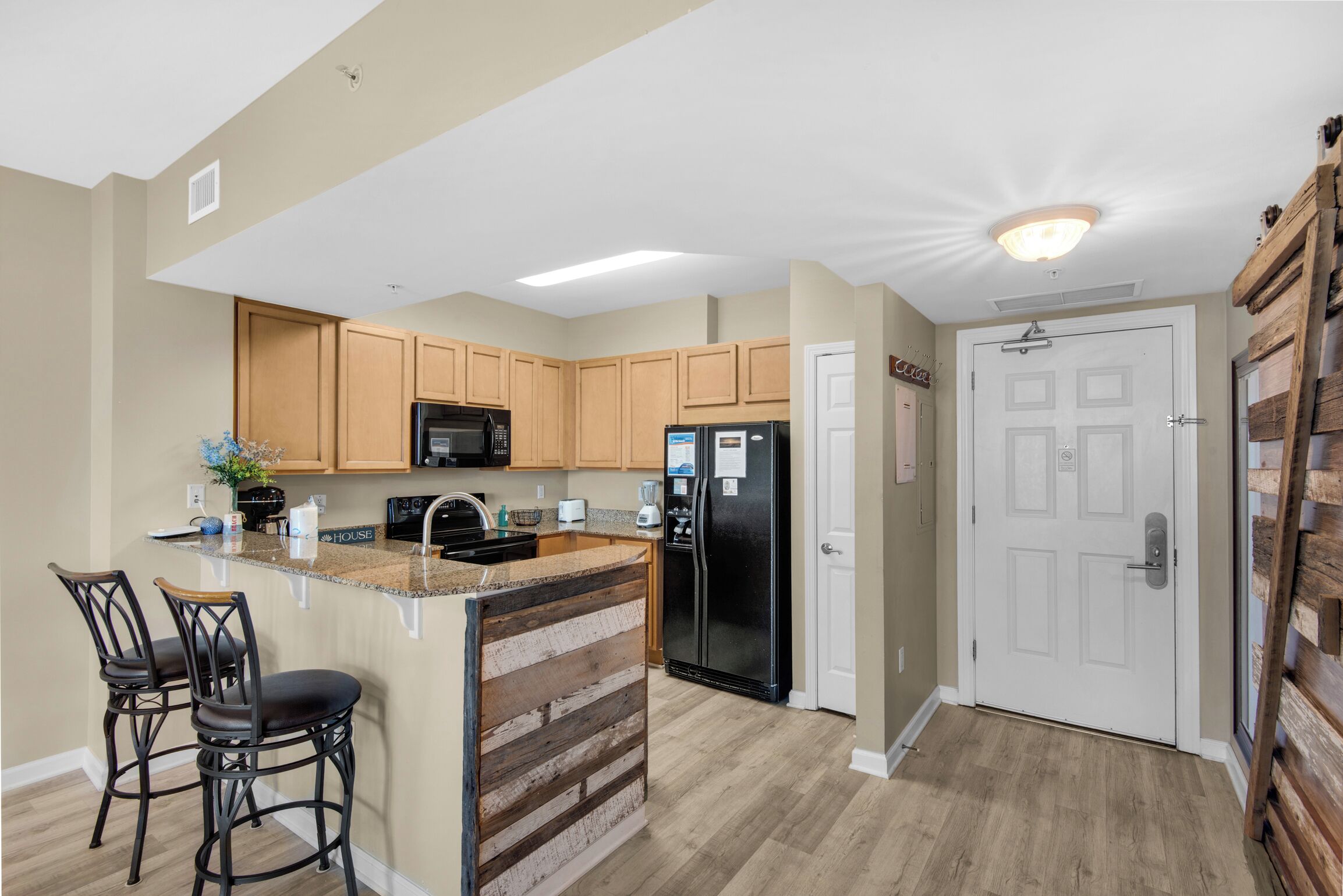 A kitchen with wooden cabinets, a black refrigerator, and a built-in island with bar stools.