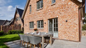 Een bakstenen gebouw met een patio tafel en stoelen, omgeven door een verzorgd gazon.