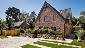 Een bakstenen huis met een kiezelpad en een houten hek.