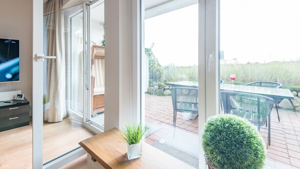 A modern living room with a large sliding glass door leading to an outdoor patio area.