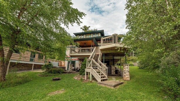 A two-story house with a balcony and a staircase leading to the upper level. - Cozy Lakefront Escape w/ Sauna, Swim Spa & Views (McHenry)