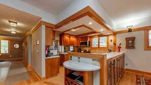 A modern kitchen with wooden cabinets, a central island, and built-in appliances. - Cozy Lakefront Escape w/ Sauna, Swim Spa & Views (McHenry)