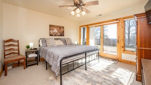 A bedroom with a bed, a chair, a nightstand, a ceiling fan, and a large window. - Epic Wisp Views w/ Fireplace, Game Room & Hot Tub (McHenry)