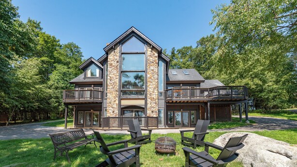 A two-story house with a stone facade, large windows, and a balcony. - Epic Wisp Views w/ Fireplace, Game Room & Hot Tub (McHenry)