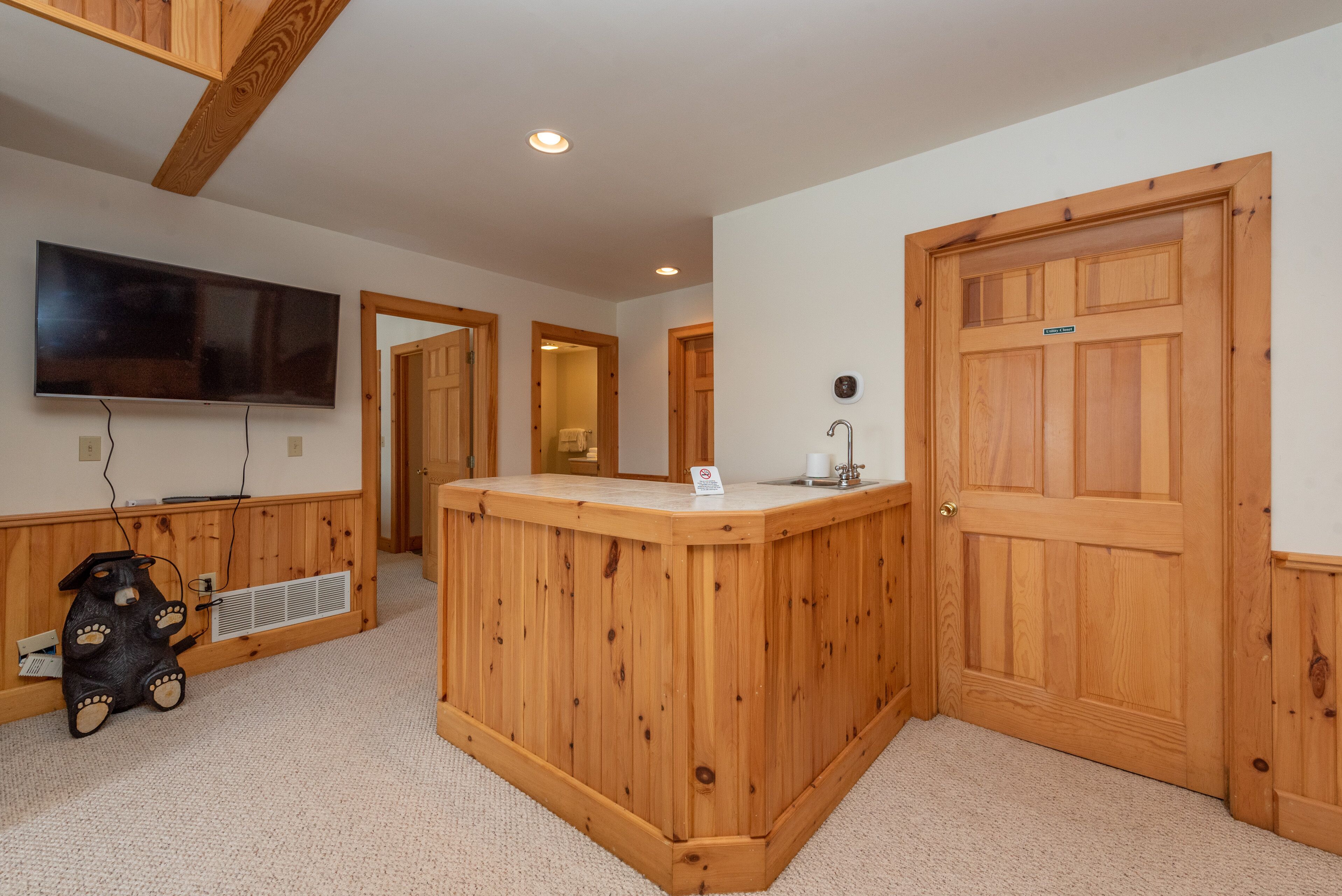 A room with a wooden reception desk, a television mounted on the wall, and a door with a sign.