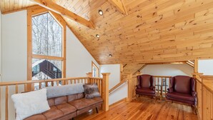 A wooden-floored living room with a brown leather sofa, two red leather chairs, and a wooden staircase. - Epic Wisp Views w/ Fireplace, Game Room & Hot Tub (McHenry)