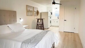 A bedroom with a bed, a ceiling fan, a nightstand, a desk, and a view into the kitchen. - Newly renovated studio apartment 1 mile to HWY 99 (Salida)