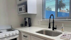 A kitchen with a stove, microwave, coffee maker, sink, and window with blinds. - Newly renovated studio apartment 1 mile to HWY 99 (Salida)