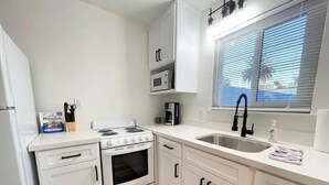 A compact kitchen with white cabinets, a stove, a microwave, and a sink. - Newly renovated studio apartment 1 mile to HWY 99 (Salida)