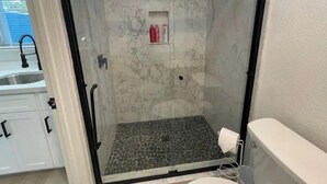 A glass-enclosed shower with a marble wall and a patterned floor. - Newly renovated studio apartment 1 mile to HWY 99 (Salida)