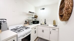 A modern kitchen with white cabinetry, a gas stove, a microwave, and a woven basket on the wall. - New & updated 2-bedroom 1 bathroom apt. Near Modesto 1mile from HWY 99 (Salida)