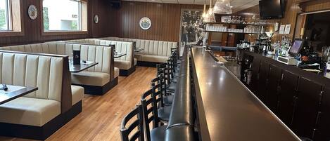 A restaurant with booth seating, a bar area, and a television screen.