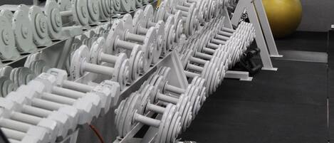 A gym with rows of dumbbells and exercise balls.