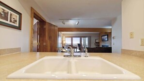 A bathroom with a large sink, wooden ceiling beams, and a framed picture on the wall. - Shanty Creek Condo - on the resort! (Bellaire)
