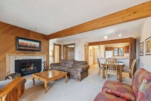 A living room with a fireplace, a sofa, a coffee table, and a dining area with chairs.