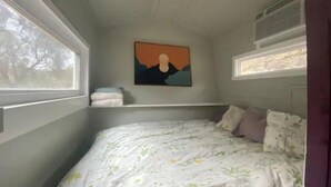 Een slaapkamer met een bed, een schilderij aan de muur en een raam.