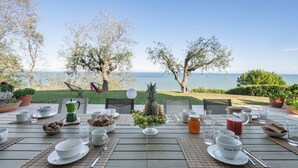 An outdoor dining table set with various dishes, glasses, and a view of the sea. - Villa Lucente 6+2, Emma Villas (Silvi Paese)