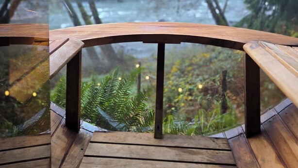 A wooden deck with a glass railing overlooking a river and forested area. - Stilly River Haus - Hot tub - Sauna - Fireplace (Granite Falls)