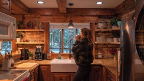 A rustic kitchen with wooden beams, a large window, and a sink. - Stilly River Haus - Hot tub - Sauna - Fireplace (Granite Falls)
