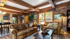 A cozy living room with leather sofas, a wooden coffee table, and a brick wall. - Stilly River Haus - Hot tub - Sauna - Fireplace (Granite Falls)